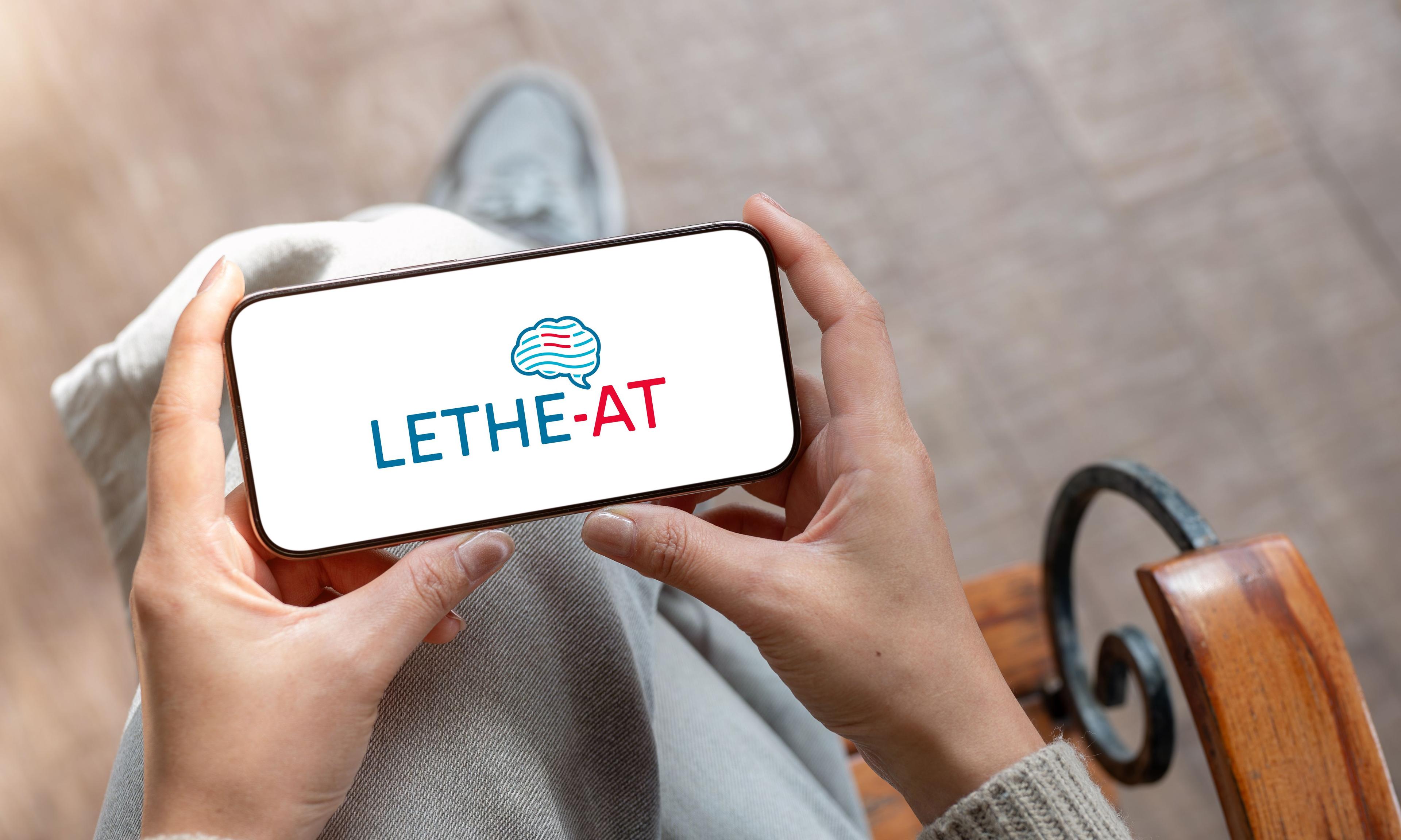 LETHE-AT-Logo auf Handyscreen, den eine Frau in den Händen hält