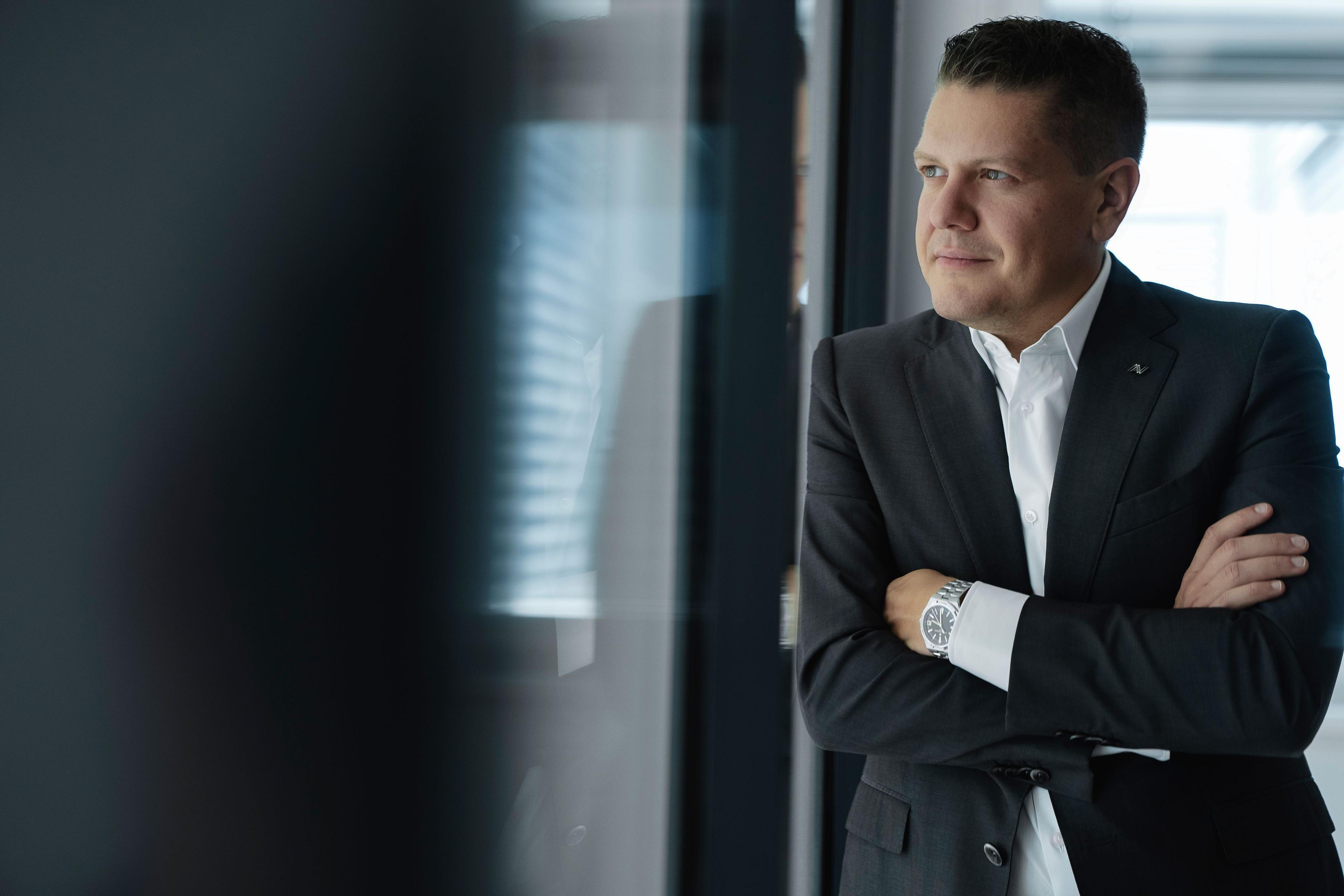 CEO Lukas Schinko blickt durch Glasscheibe in die Ferne 