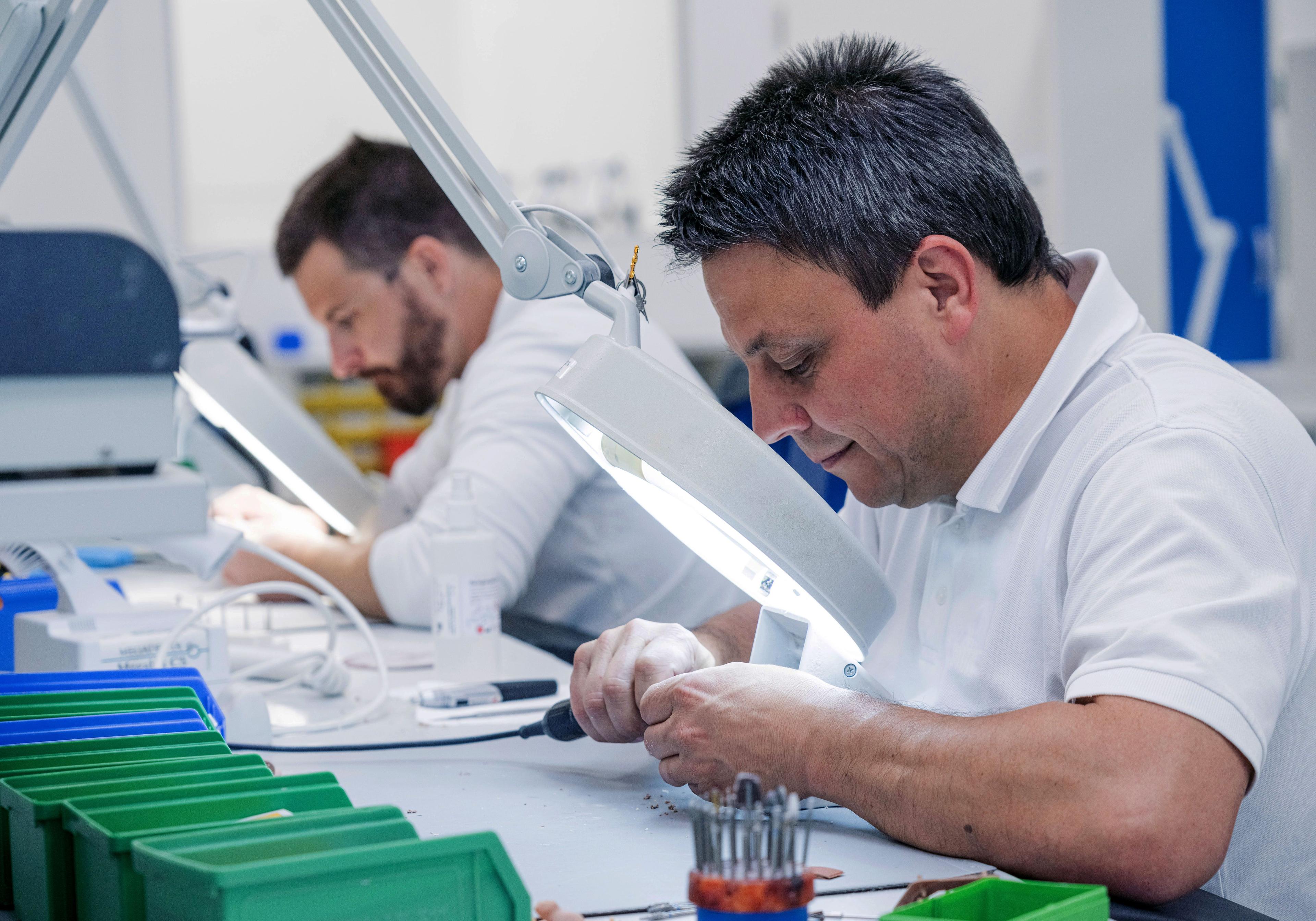 Zwei Neuroth-Mitarbeiter passen Otoplastiken für Hörgeräte im Labor in Lebring individuell an