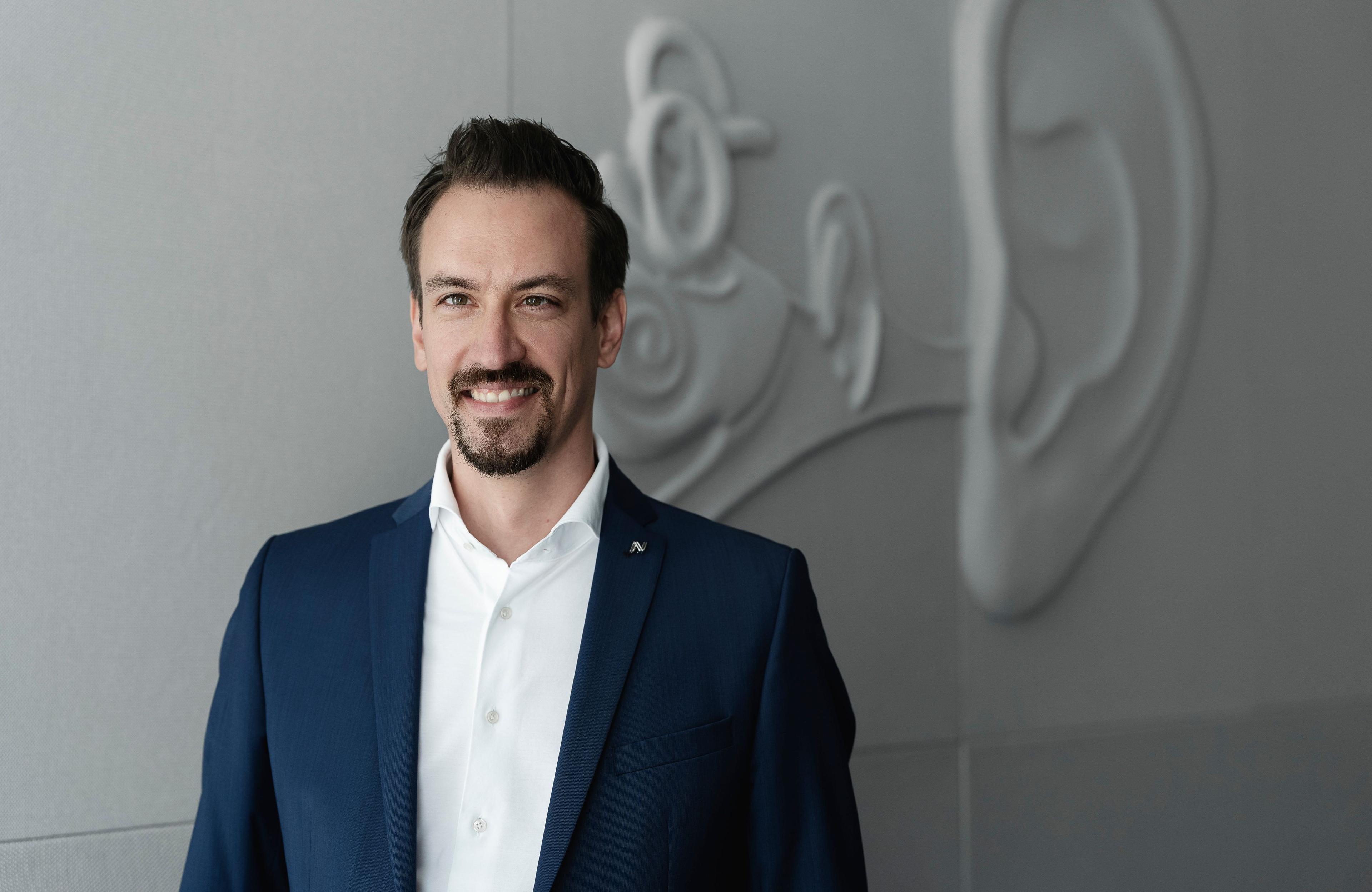 Neuroth-Pressesprächer Thomas Huber vor grauer Ohrenwand 