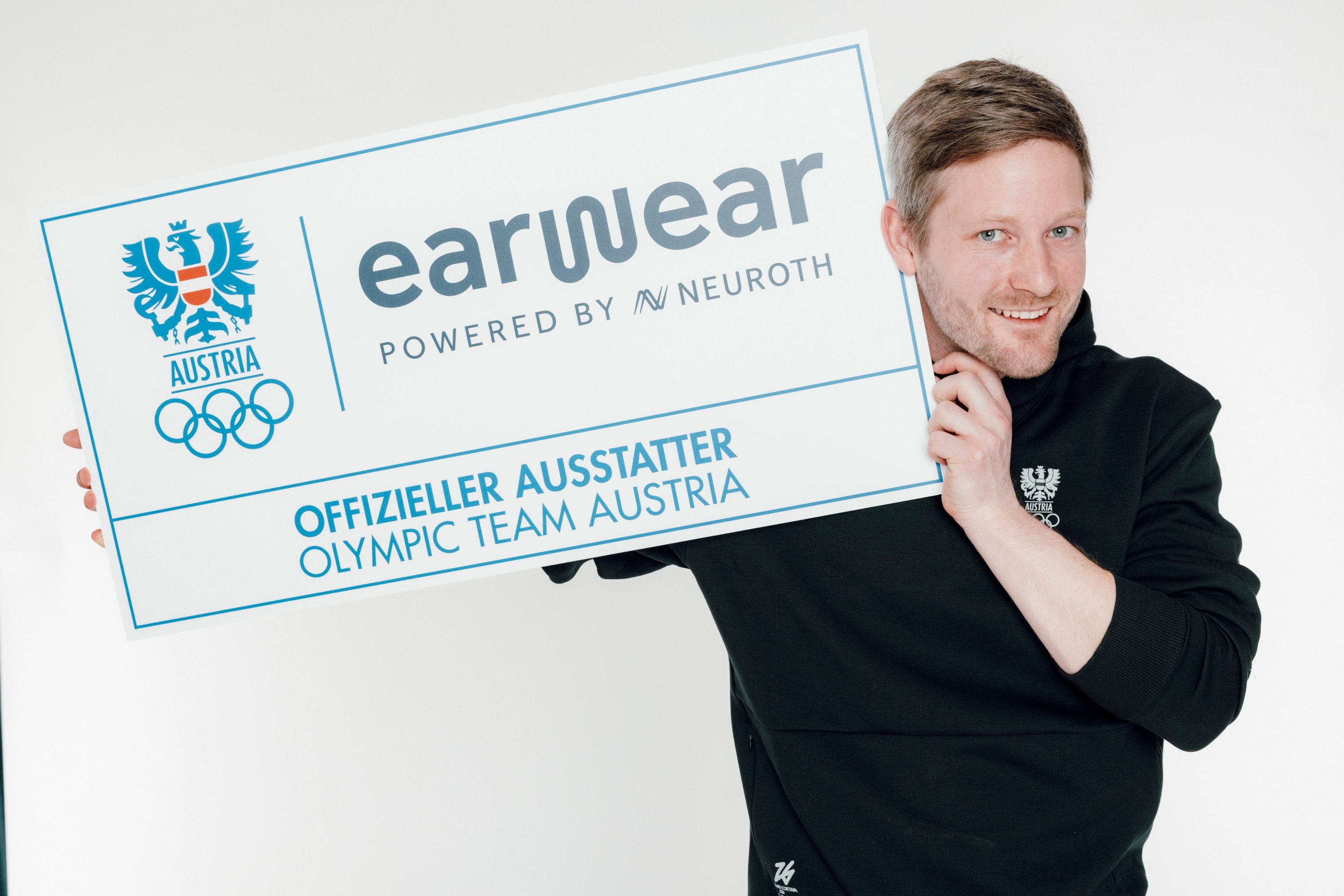 Athlet hält offizielles Ausstatter-Schild in die Kamera